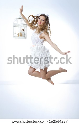 model dressed in white jumps holding a cage to represent freedom
