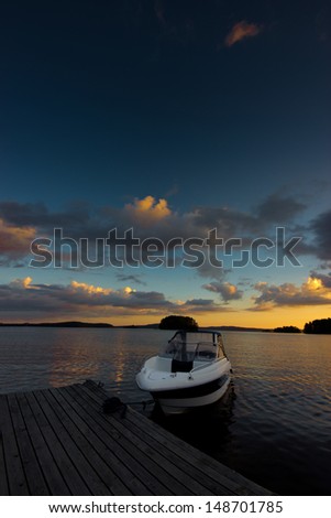 A power boat moored against a sunset on a calm lake