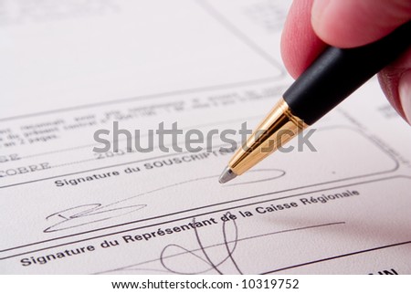 Close up of a hand signing a document. Please note that the signature is fictitious.