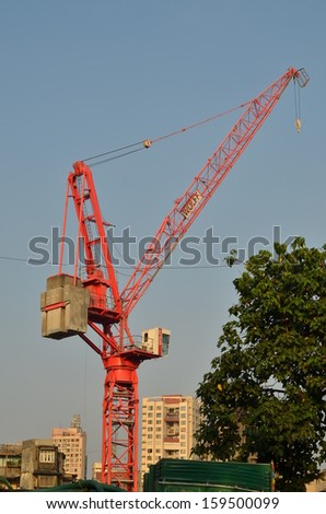 Red crane at construction site against blue sky