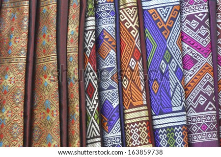 Colourful silk clothes with intricate embroideries in traditional Laotian patterns in various colors