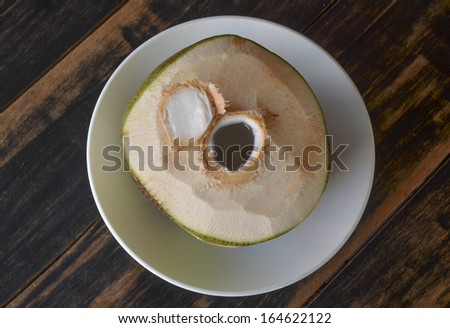 Fresh young coconut top-cut opened with dark brown wood table top as background
