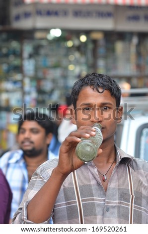 Mumbai, India - circa January 2014 -  Young man drinking soda from a bottle on the street side