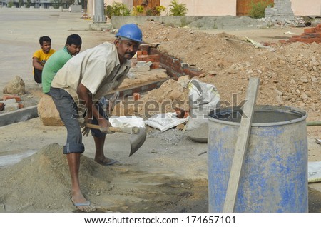 Mumbai, India - January 16, 2014 - worker mixing cement at construction site in Mumbai
