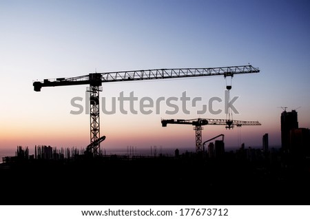 Silhouette  construction crane on top of under-construction building at sunset