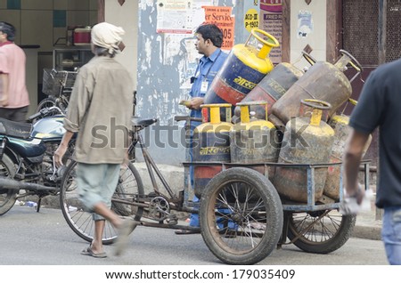 MUMBAI, INDIA - FEBRUARY 10, 2014: Man delivering LPG cylinders from his push car on busy street near Colaba market
