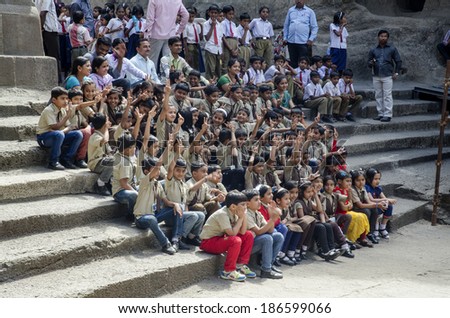 Aurangabad, India - February 14, 2014 -  school students sitting on rock steps with teachers standing behind at  Ellora Rock Cut Caves, UNESCO World Heritage site during their field trip