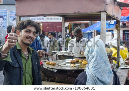 Jaipur, India - February 27, 2014 - Street food vendor greeting while preparing meal and snack for customers at local market during daytime