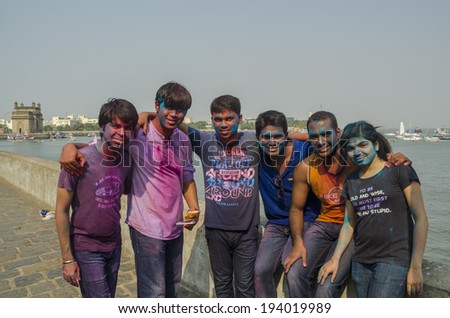 MUMBAI, INDIA - MAR 16, 2014 -  Group of young men and girls  with colors on their faces celebrating Holi Festival of colors near Gateway of India in Mumbai