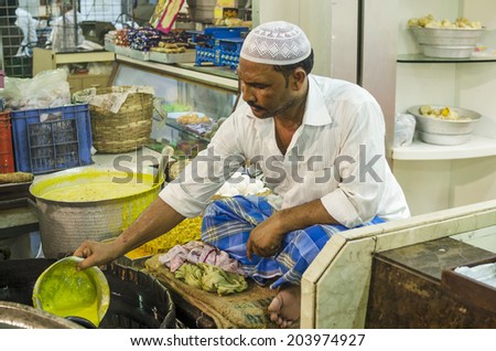 Mumbai, India - July 3, 2014 -  Muslim man frying snack in hot oil pan from stall at crowded Mohammad Ali Road in the evening during Ramzan fasting month