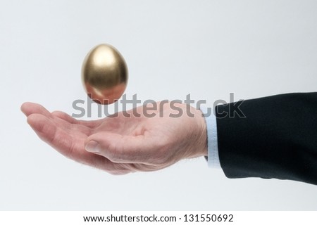 Man\'s Open Hand with a Golden Egg Suspended Above His Palm