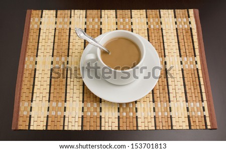 the white mug with hot coffee is located on a dark tree table