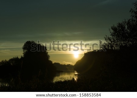 morning hour when the sun rises over the river surrounded with trees