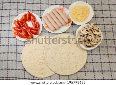 ingredients for preparation of pizza are spread out on plates and are ready to use