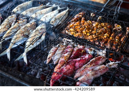 Grilled fresh seafood: prawns, fish, octopus, oysters food background Barbecue / Cooking BBQ seafood on fire / Indonesia