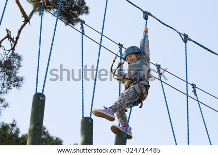 Girl climbing in adventure park , rope park