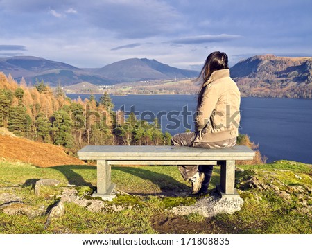 Bench with woman at Derwent Water, Lake District, UK.