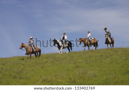 Friends on a horseback trail ride against a blue sky