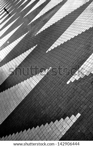 Lonely man is going away on empty square with zigzag pattern. Black and white photo.