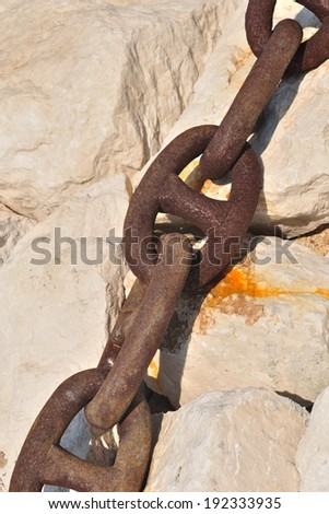 Detail view of old rusty ship chain on stone