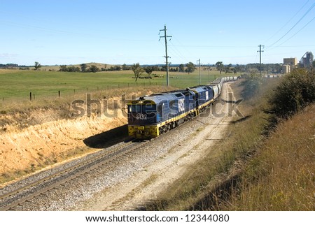 A train travelling on a single line between an industrial complex and the main line