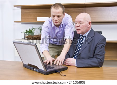 A company director being shown how to operate a laptop by a computer technician