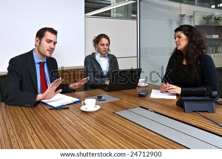 Three staff members discussing business matters in front of a presentation screen