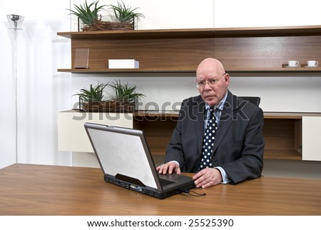 A company director sitting at his desk in front of a laptop