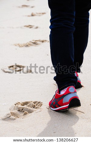 Closeup of woman\'s feet walking on sand in sport shoes