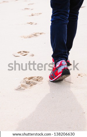 Closeup of woman\'s feet walking on sand in sport shoes