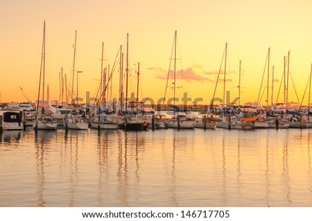 Yacht port over orange sunset with row of luxury sailboats,water transport, ocean transportation, beautiful vessel in the harbor, summer vacation, active lifestyle, holiday concept