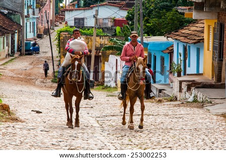 TRINIDAD, CUBA - NOVEMBER 18, 2013: Two Cuban men are riding horses in Trinidad, Cuba. Trinidad has been one of UNESCOs World Heritage sites since 1988.