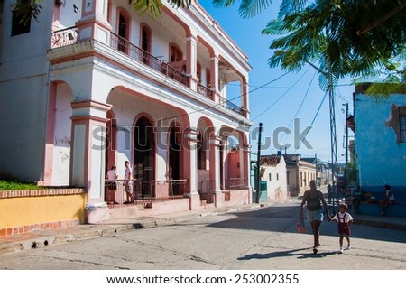 SANTIAGO DE CUBA, CUBA - NOVEMBER 12 - Local people and students are walking on the street of Santiago de Cuba. The pink house is where Fidel Castro lived from 1931 to 1933.