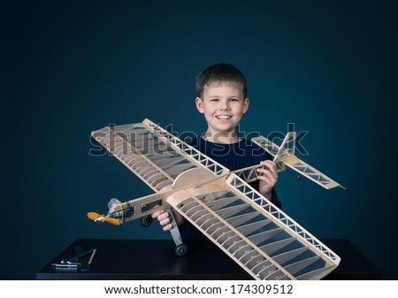 Creating the model plane. Happy boy holding wooden model plane.