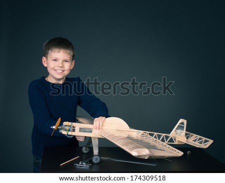 Creating the model plane. Happy boy with wooden model plane.