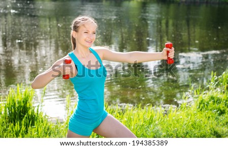 Fitness exercise woman using dumbbells in fitness strength training workout outside on grass.
