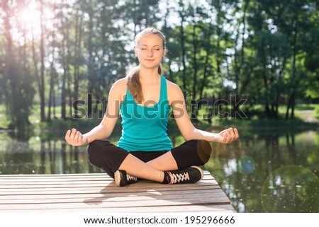 Young Woman doing Yoga Exercises Outdoor. Beautiful Girl practicing yoga in the park.