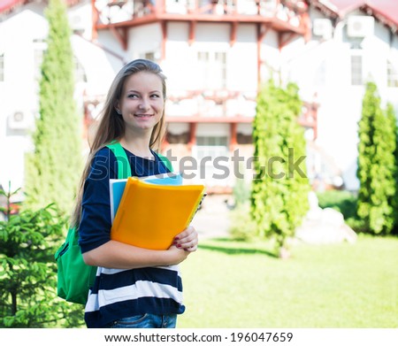 Student girl outside in summer park smiling happy. College or university student young woman with school bag and books.