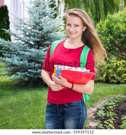 Student girl outside in summer park smiling happy. College or university student young woman with school bag.