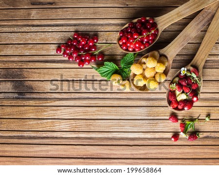 Berries on Wooden Background. Summer or Spring Organic Berry over Wood. Strawberries, Raspberries, Red currant . Agriculture, Gardening, Harvest Concept. Berries and wooden spoons on an old board.