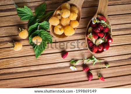 Berries on Wooden Background. Summer or Spring Organic Berry over Wood. Strawberries, Raspberries. Agriculture, Gardening, Harvest Concept. Top view . Autumn berries and wooden spoons on an old board