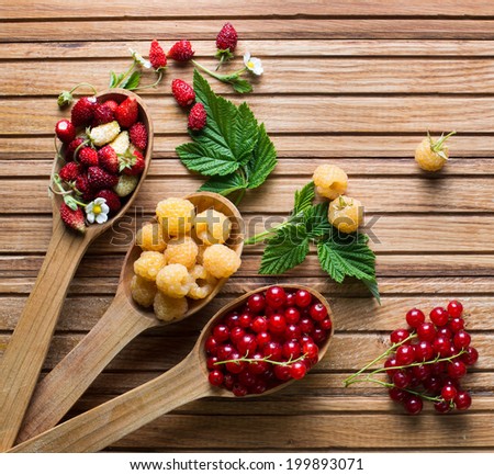 Berries on Wooden Background. Summer or Spring Organic Berry over Wood. Strawberries, Raspberries, Red currant . Agriculture, Gardening, Harvest Concept. Berries and wooden spoons on an old board