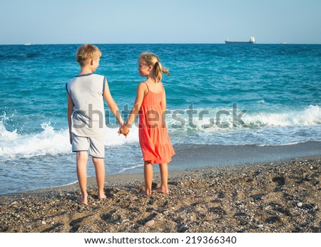 Photo of happy children friends or brother and sister looking to each other at sea beach.