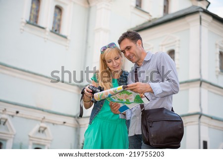 Summer holidays, dating and tourism concept  middle aged couple with camera and city map. Happy tourists sightseeing city with map.