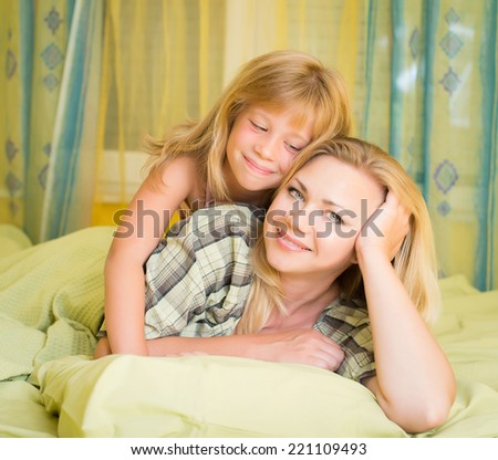 Mother and her little daughter lying in bed and smiling. Family. bed time.