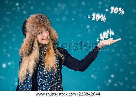 Happy surprised woman showing pointing on discounts 50%, 30%, 20%. Winter sale concept.