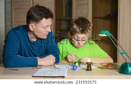 Creating the model plane. Happy son and his father are making aircraft model. Hobby and family  concept.