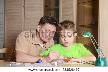 Creating the model plane. Happy son and his father are making aircraft model. Hobby and family  concept.