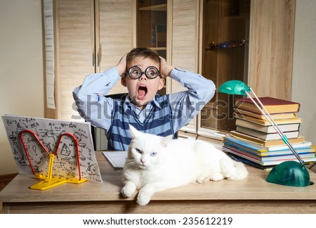 Crazy Boy Wearing Funny Glasses Doing Homework With Cat Sitting On The Desk. Child With Learning Difficulties. Boy Having Problems With His Homework. Panic. Education Concept.