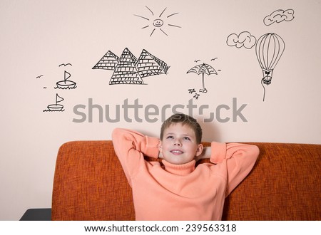 Boy sitting on sofa dreaming about vacation. Child dreaming of traveling.